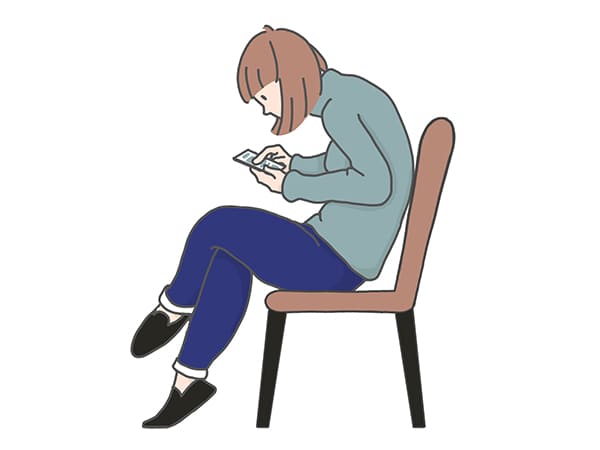 猫背でスマホを操作する女性